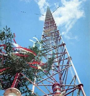 Looking up the red-and-white lattice of the Konstantynów radio mast against a blue sky